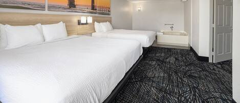 Una habitación de hotel con dos camas, un baño y un cuadro grande de un faro en la pared.