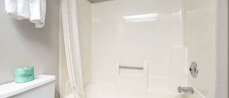 A bathroom with a bathtub, a toilet, and a shower curtain.