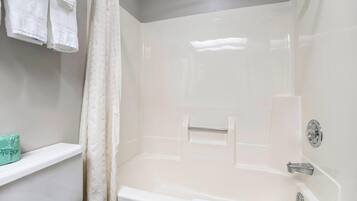 Un baño con una bañera, un cortinón de ducha, un tendedero para toallas y una estantería con una caja de pañuelos.
