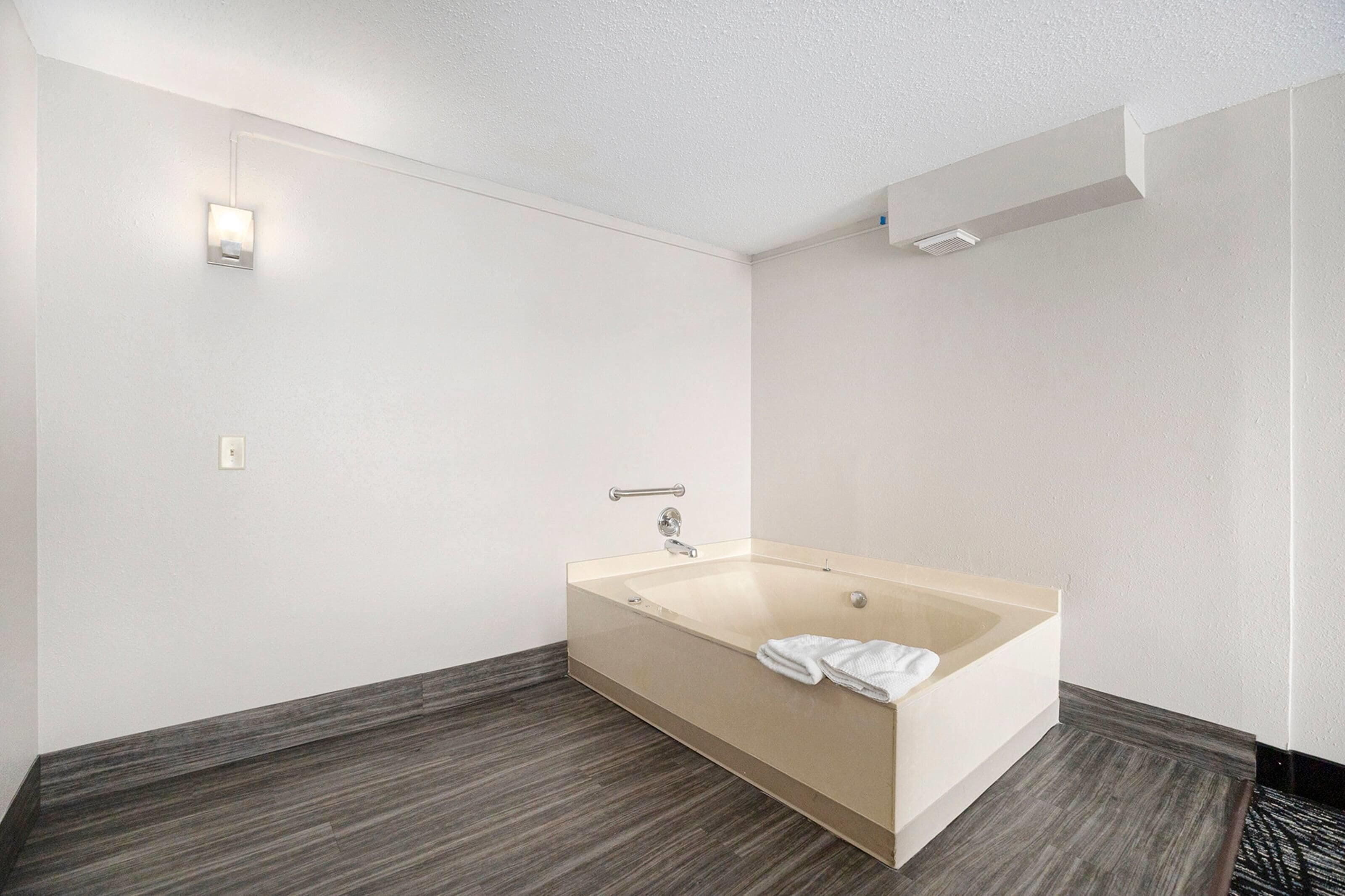 A modern bathroom with a freestanding bathtub, a towel, and a wall-mounted light fixture.