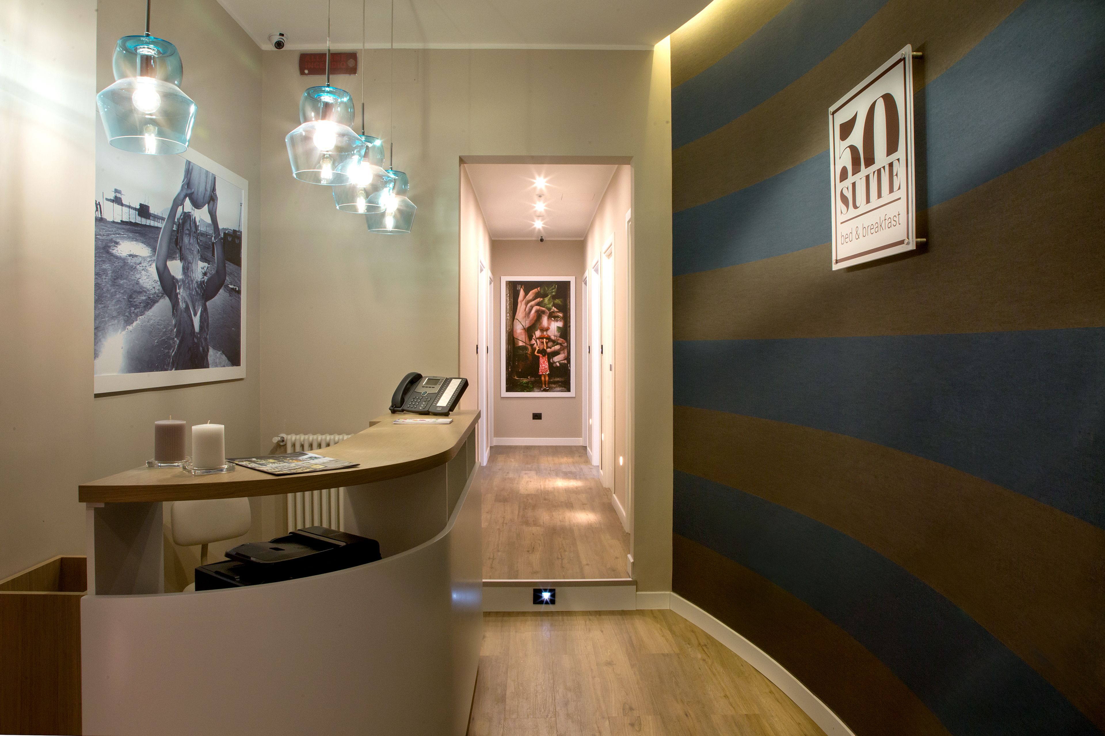 Zona de recepció d'hotel amb mostrador, telèfon i un cartell a la paret.