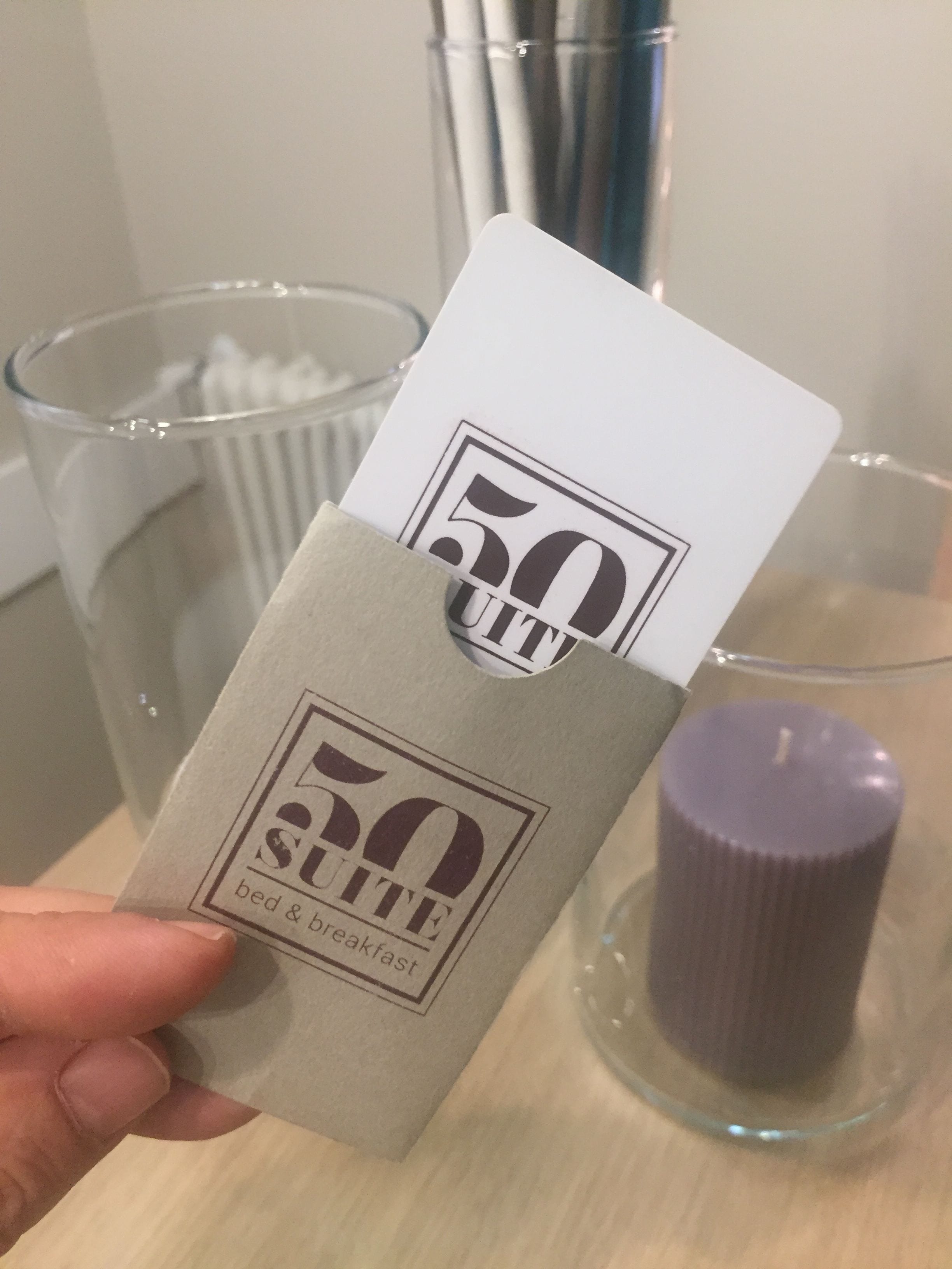 A hand holding a beige card with "50 suite bed & breakfast" printed on it.