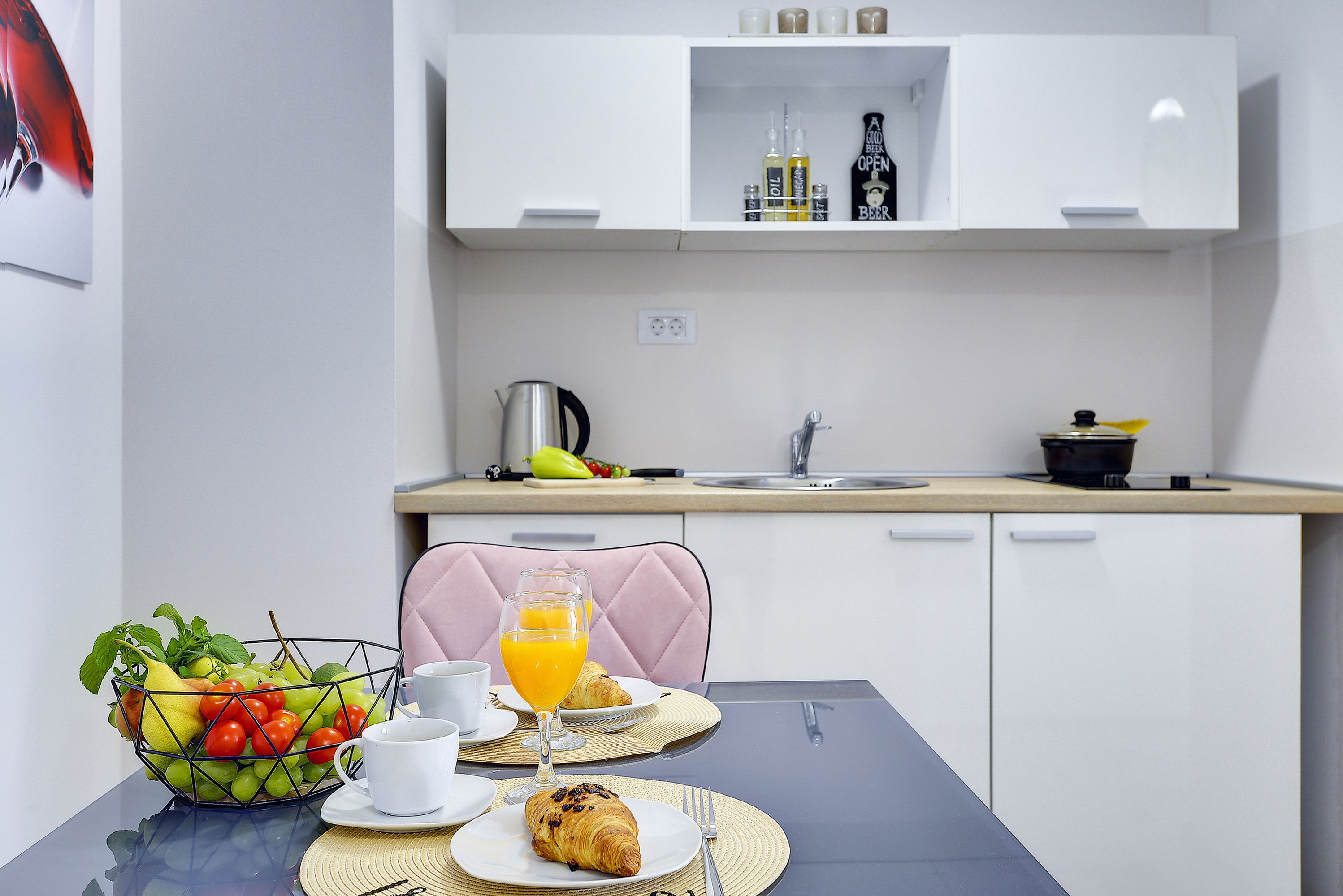 Una mesa con desayuno: frutero, croissant y jugo de naranja.