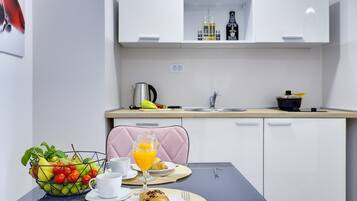 Una mesa con desayuno: frutero, croissant y jugo de naranja.