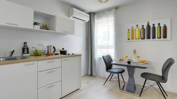 A modern kitchen with white cabinets, a wooden countertop, and a dining area with a table and chairs.