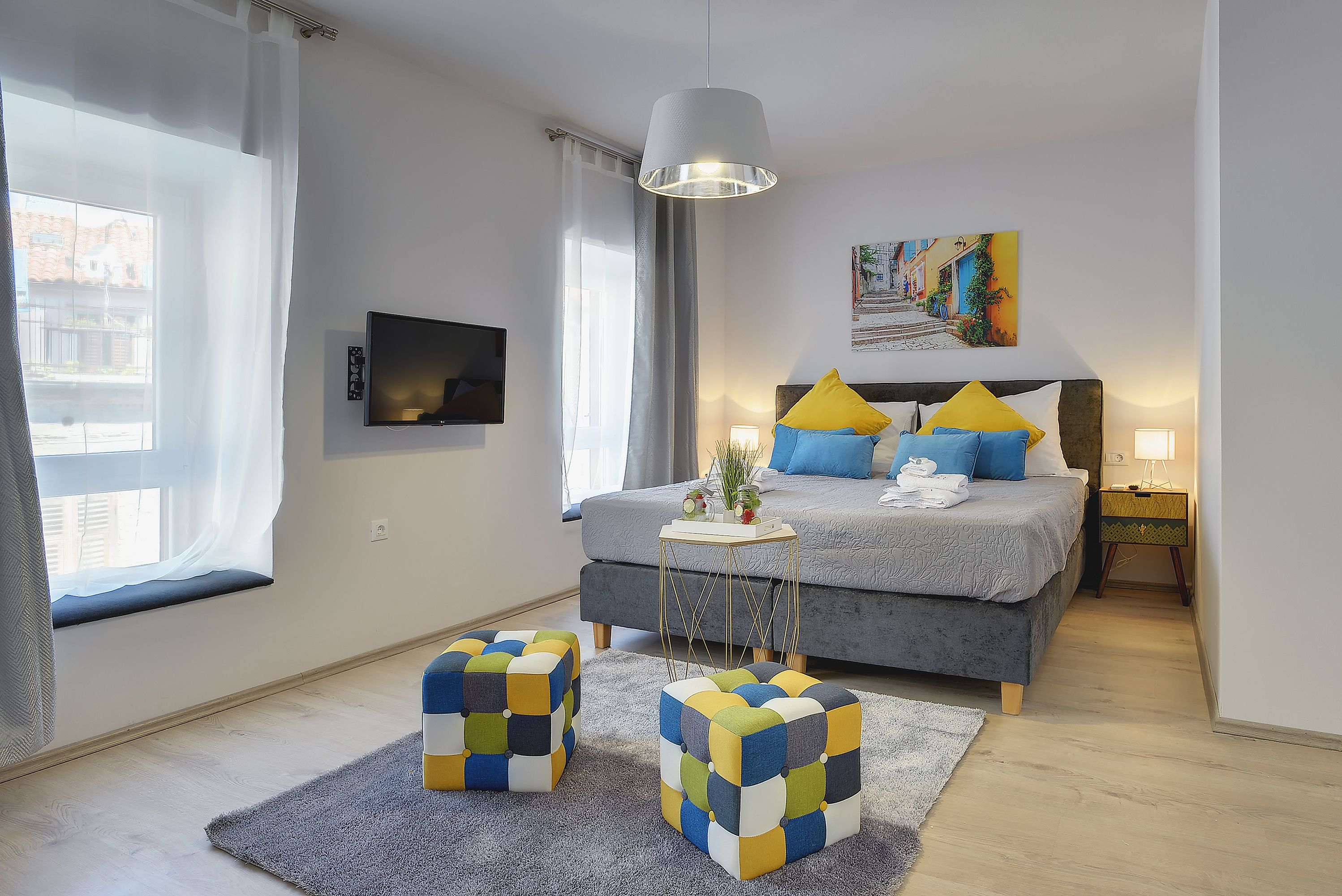A modern bedroom with a bed, bedside table, and a view of the city.