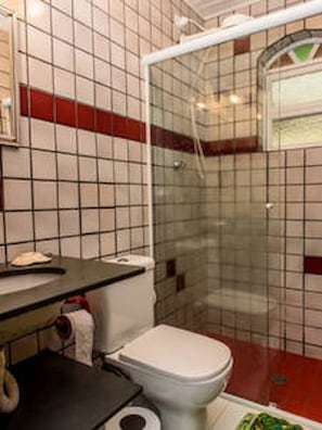 A bathroom with a toilet, sink, and shower enclosure. - Casa Cantinho em Ilhabela (Ilhabela)