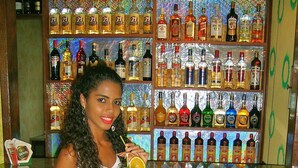 Una persona sentada en la barra, con diversas botellas de licor al fondo.