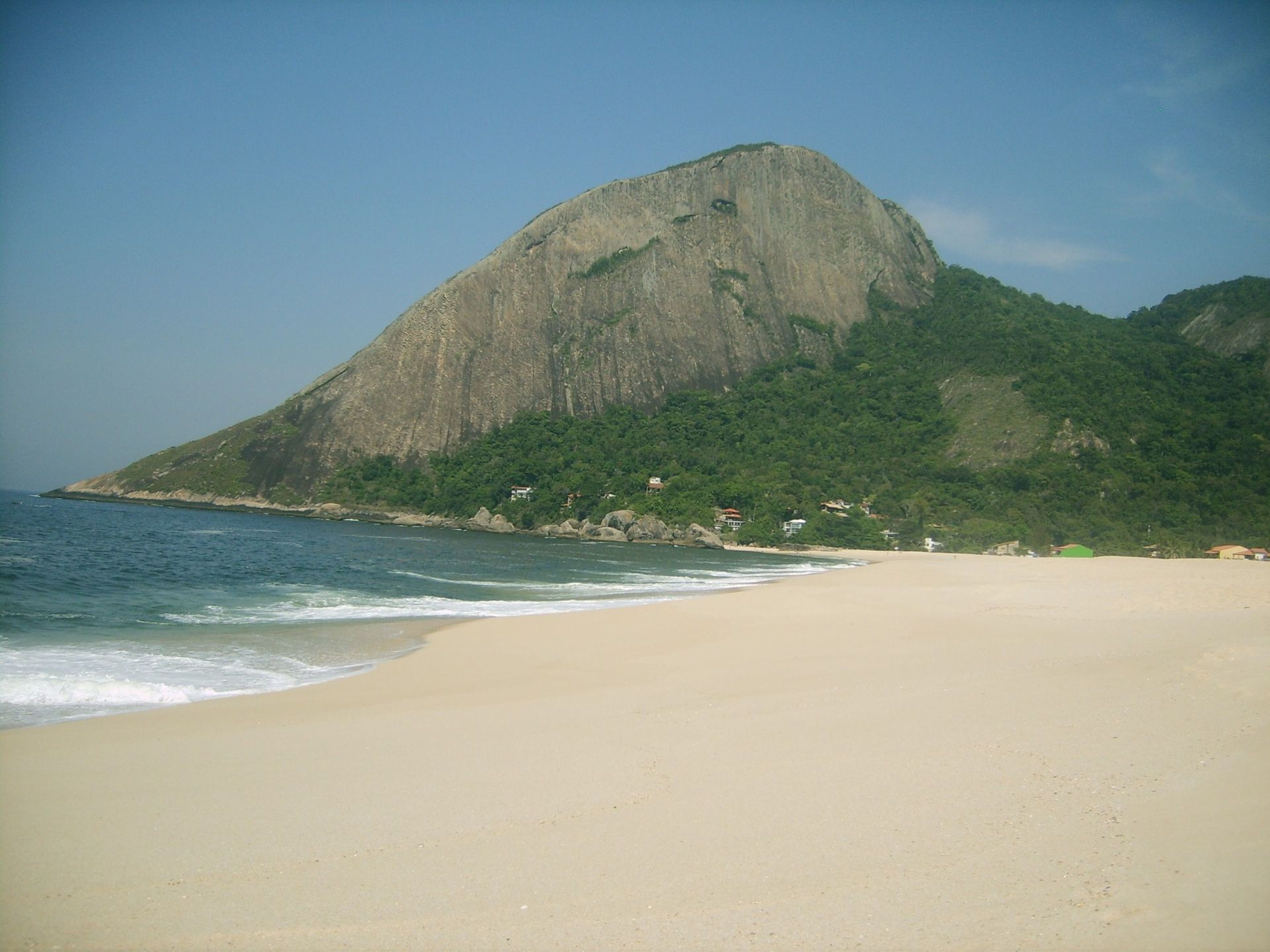 Een strand met een grote berg op de achtergrond.