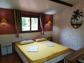 Una habitación con una cama, dos lámparas de pared, un ventanal con cortinas, un reloj de pared y un mural tropical.