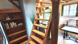 Una escalera espiral de madera en una habitación con una estantería y una mesa.
