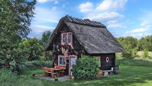 A rustic wooden house with a thatched roof, a wooden bench, and a small table.