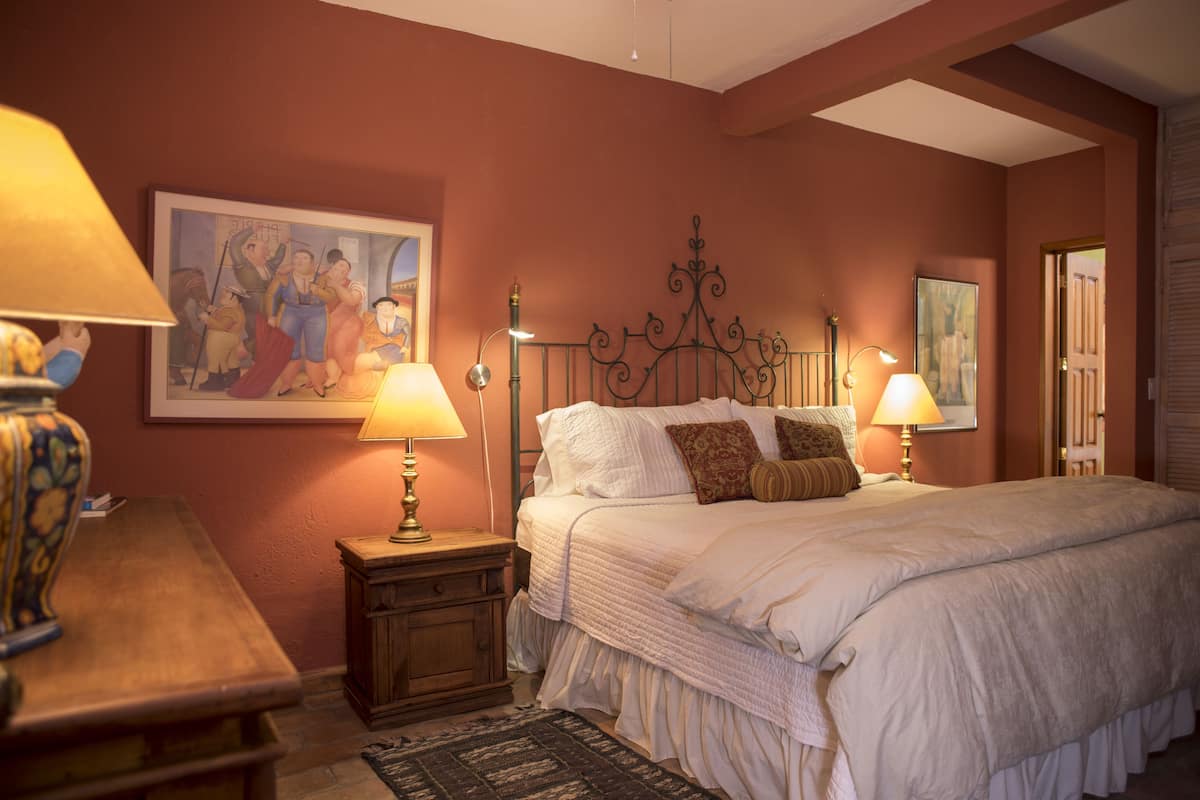 Une chambre à coucher avec un grand lit, deux lampes de chevet, une table de chevet, une commode en bois et un tableau au mur.