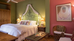 Un dormitorio con cama con dosel, dos lámparas de noche, una mesita de noche de madera, una pequeña mesa y una silla.