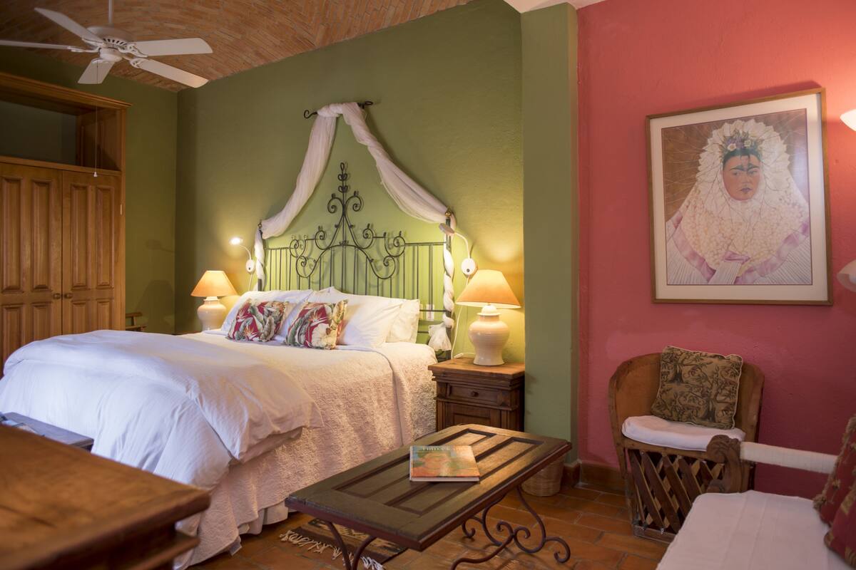Une chambre à coucher avec un lit à baldaquin, deux lampes de chevet, une table de chevet en bois, une petite table et une chaise.