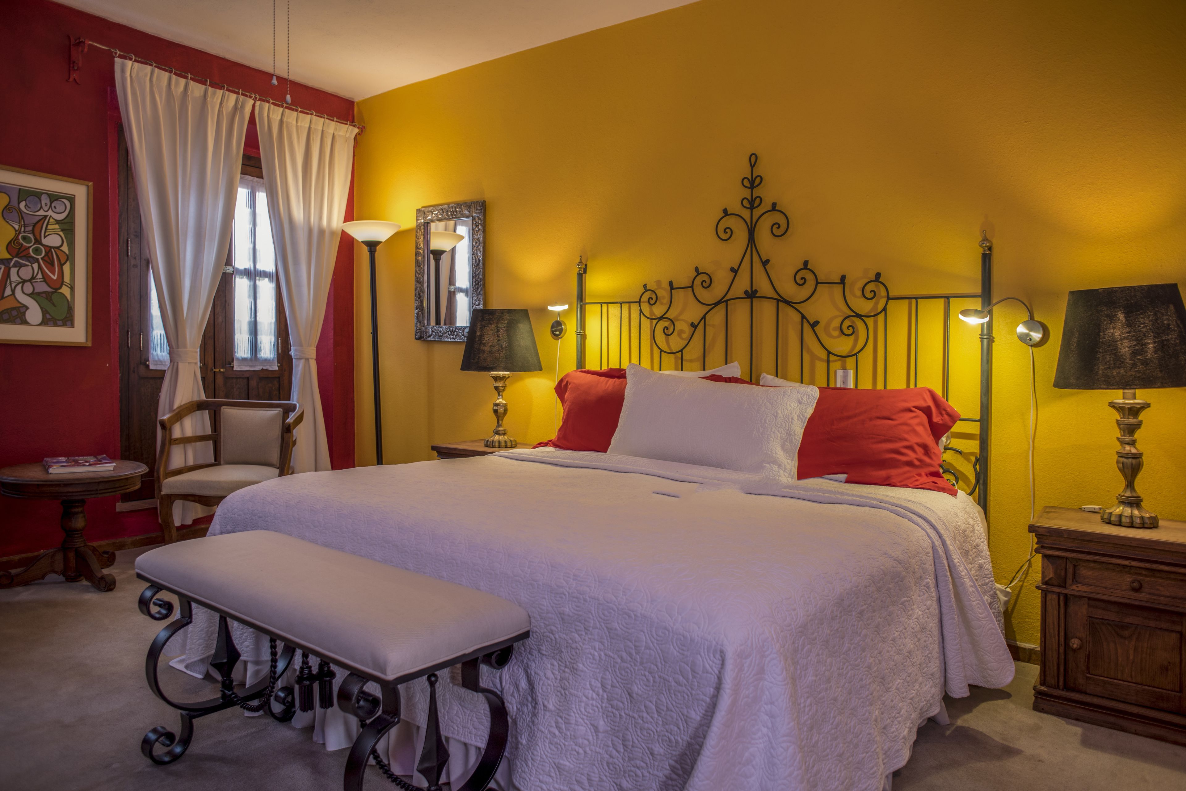 Une chambre bien rangée, avec un lit, des tables de chevet, une chaise et un banc.