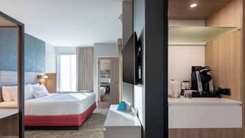 Habitación de hotel con cama, escritorio, televisión y cafetera.