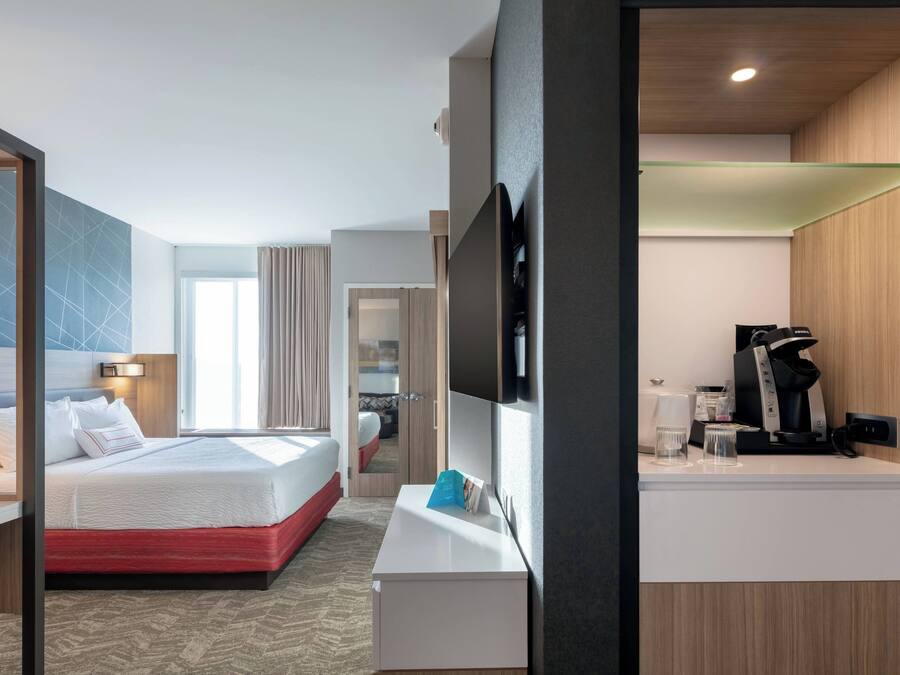 Ein Hotelzimmer mit Bett, Schreibtisch, Fernseher und Kaffeemaschine.
