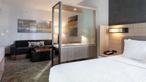 Quarto de hotel moderno com uma cama grande, um sofá, uma escrivaninha e um banheiro.