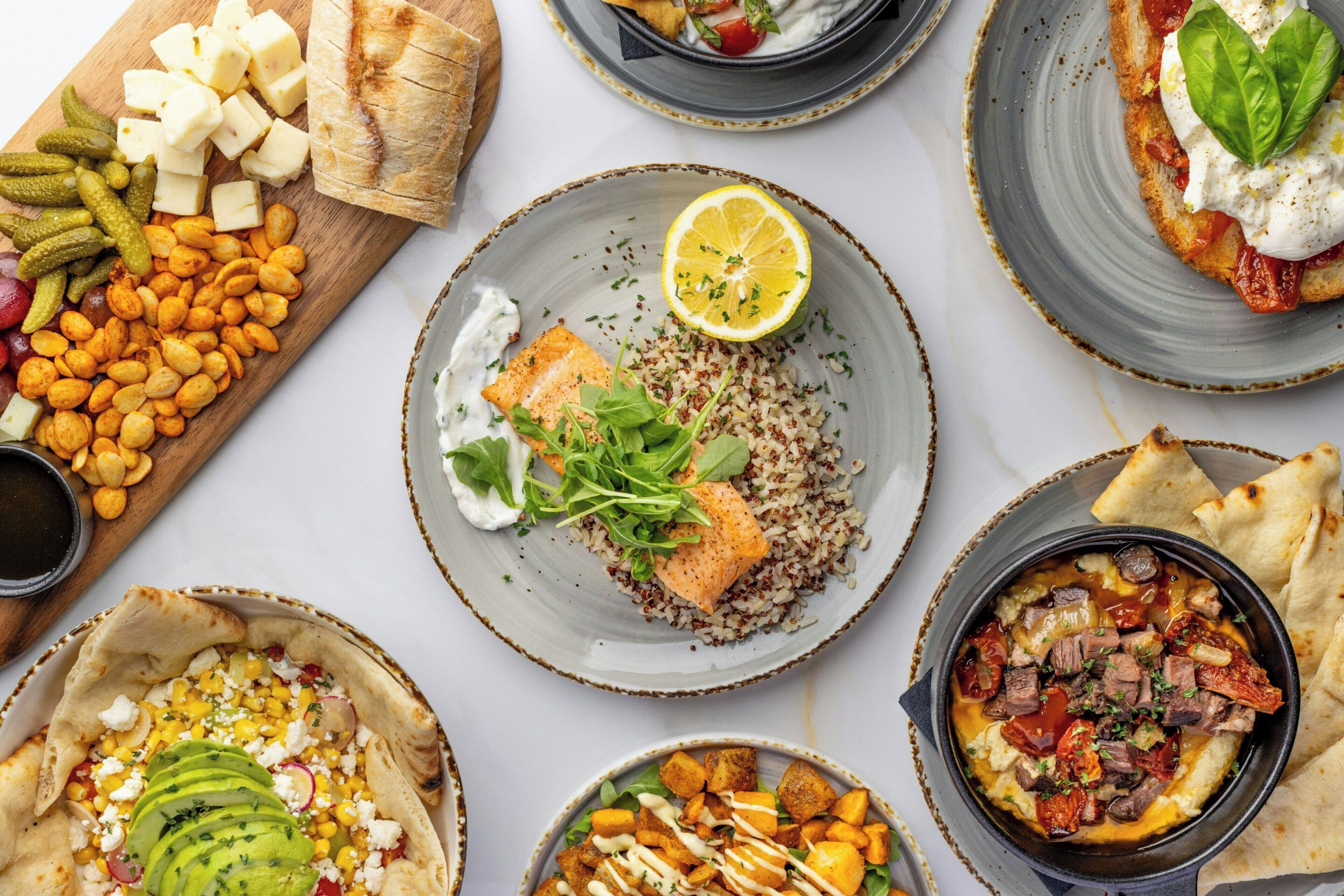 A variety of dishes including salmon, quinoa, and a bowl of meat with vegetables.