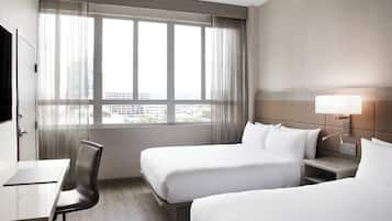 Quarto de hotel com duas camas, uma escrivaninha e uma cadeira.