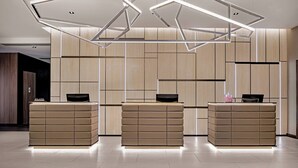 Een modern receptiegebied met drie receptiebalies, elk voorzien van een flatscreenmonitor en een klein decoratief object.