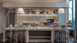 Een moderne keuken met een centraal kookeiland, barkrukken en hanglampen.