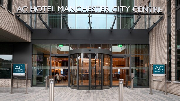 Het uiterlijk van het AC Hotel Manchester City Centre, met een glazen ingang en een draaideur.