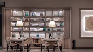 Een moderne bibliotheek met boekenkasten, een tafel met stoelen en een ingelijste kunstwerk aan de muur.