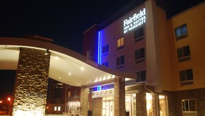 Entrada de un hotel con fachada de piedra y un letrero que dice "Fairfield Inn & Suites by Marriott".