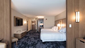 Una habitación de hotel con una cama grande, un escritorio, una silla, un tocador y un televisor.