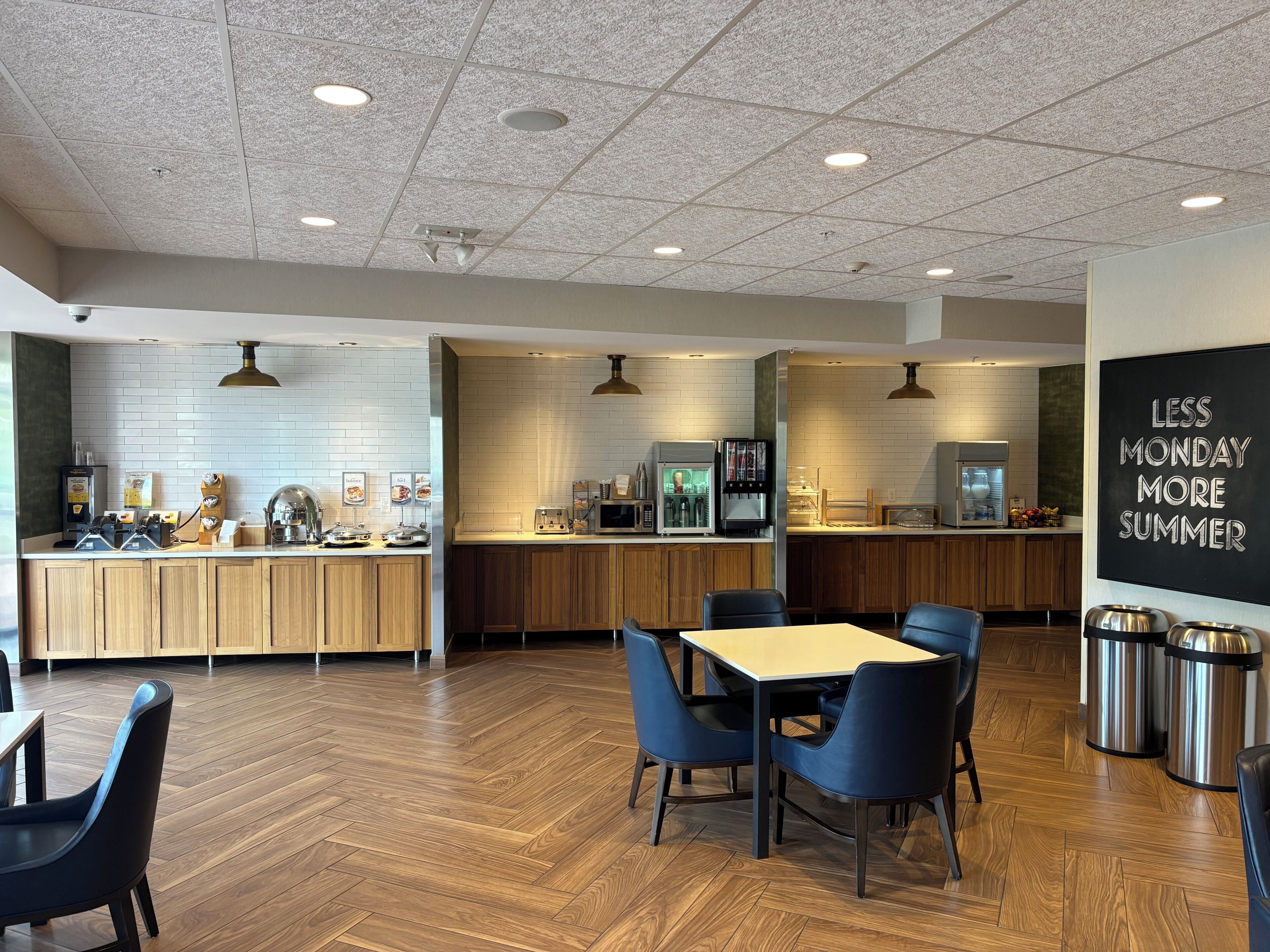 A modern cafe with a wooden counter, seating area, and a chalkboard sign.