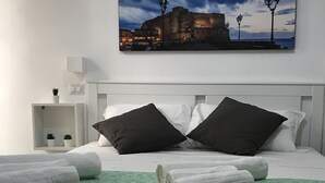 Une chambre d’hôtel avec un lit, des oreillers, un tapis vert et deux tasses posées sur une table.