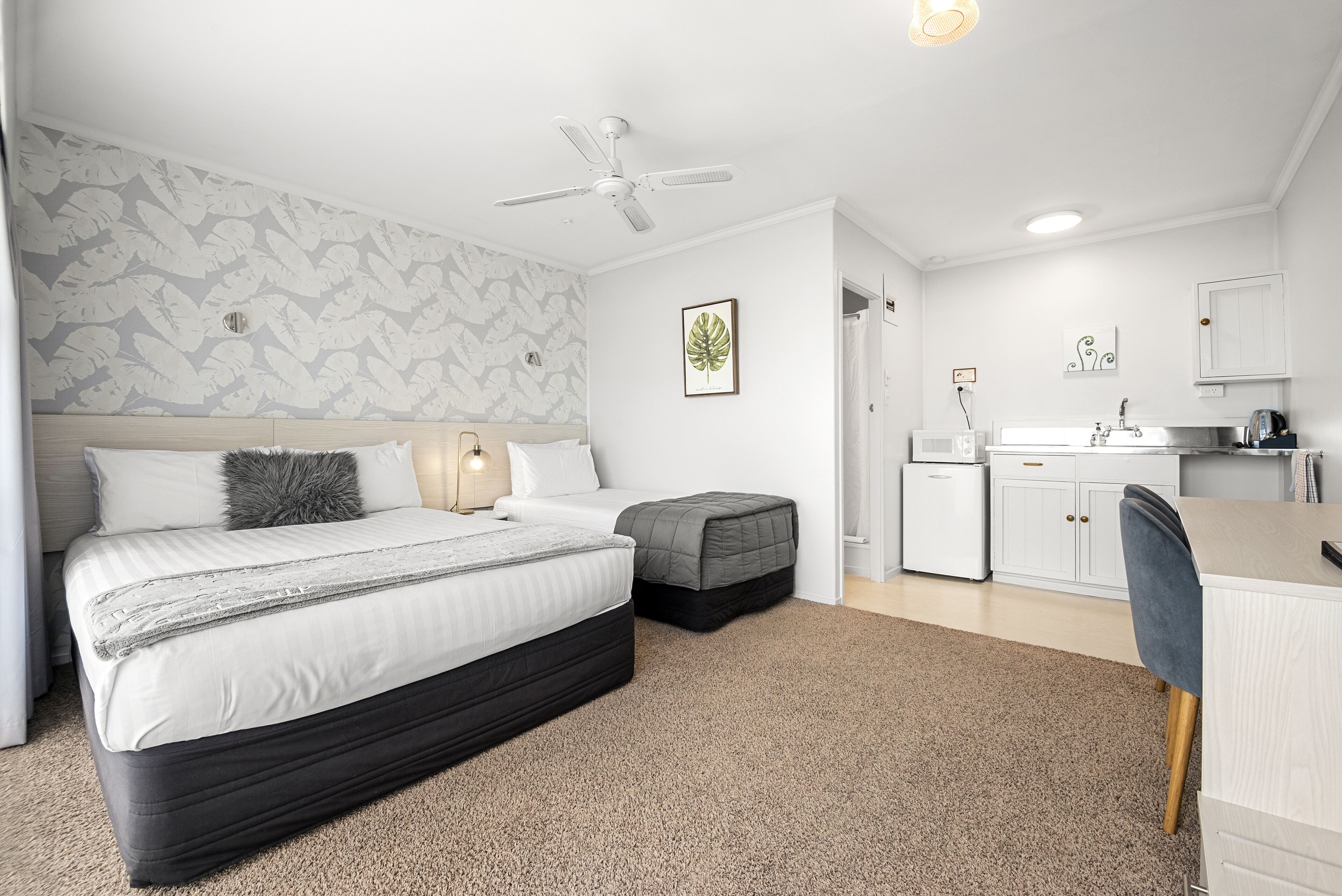 A bedroom with a bed, bedside table, and a small desk area with a chair.