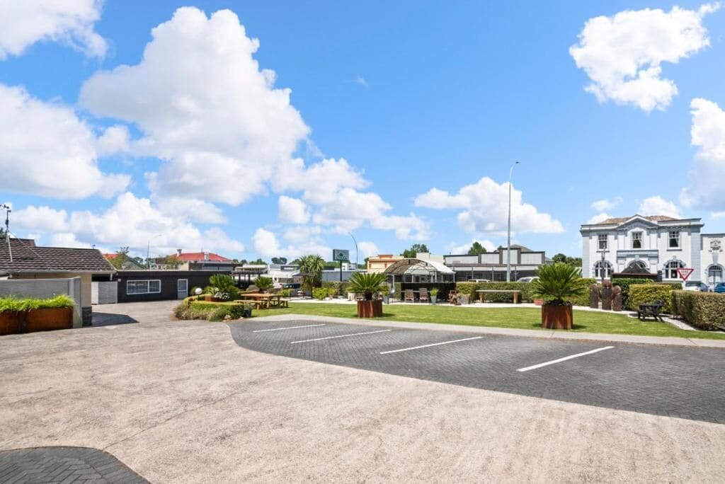 A parking lot with a paved walkway, a grassy area with a bench, and a building with a dome roof.