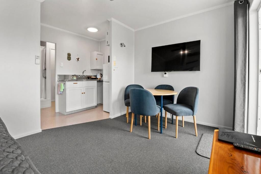 A modern living space with a dining area, kitchen, and a flat-screen TV mounted on the wall.