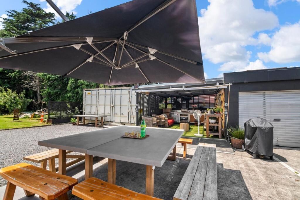 An outdoor patio area with a table and benches, a covered seating area, and a storage building in the background.