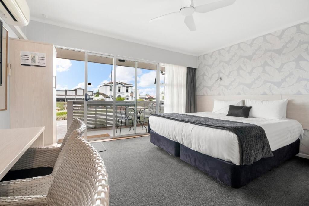 Una habitación de hotel con cama, escritorio y balcón con vista a un edificio.