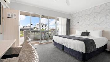 Una habitación de hotel con cama, escritorio y balcón con vista a un edificio.