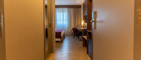 Ein Hotelgang mit einem Bett, einem Schreibtisch und einem Stuhl.