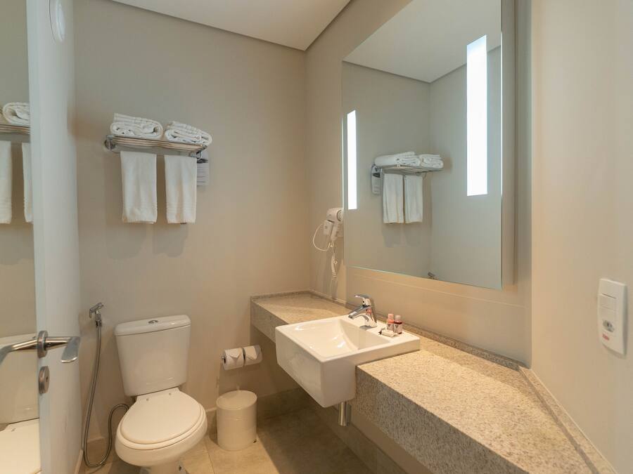 Un baño moderno con inodoro, lavamanos y toalleros.