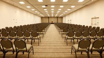 Une salle de conférence avec des rangées de chaises disposées face à une scène.