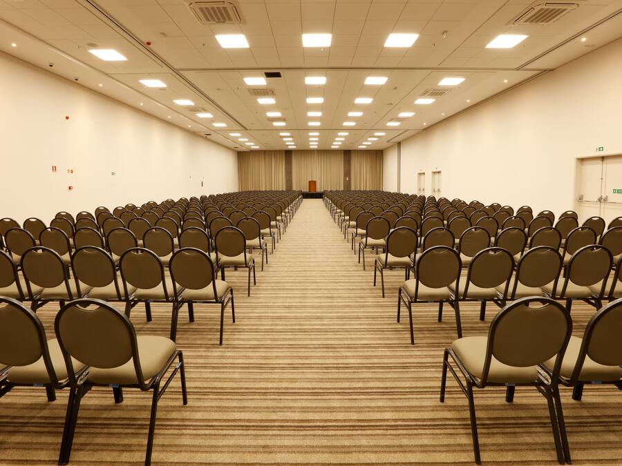 Une salle de conférence avec des rangées de chaises disposées face à une scène.
