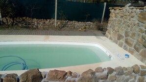 Una piscina rectangular rodeada por un muro de piedra.