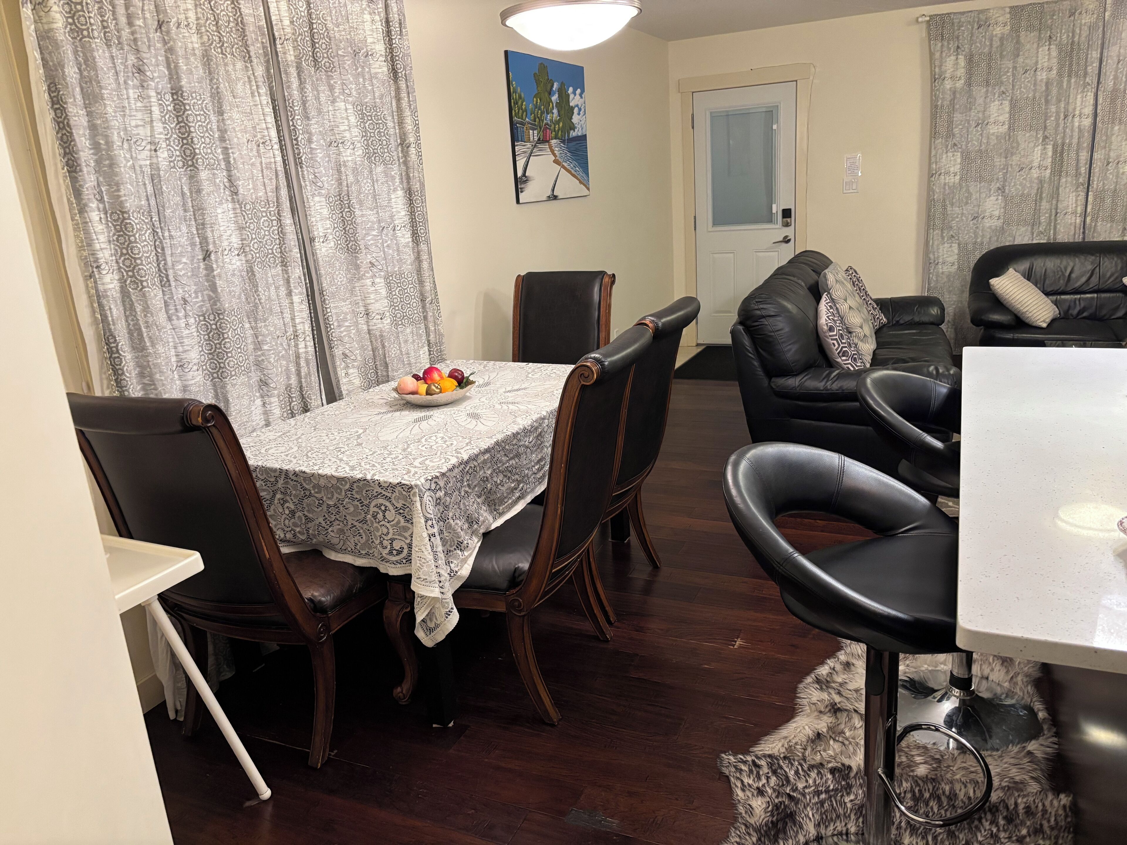 En matplats med ett bord dukat för fyra personer, en svart lädersoffa och en tavla på väggen.