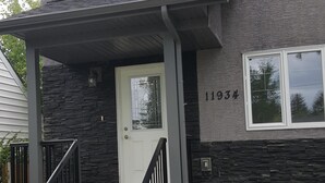 A two-story house with a stone facade, a front porch with a railing, and a number '11934' on the wall. - Modern Vacation Home Near West Edmonton Mall, Transit Center & LRT - 3BR (Edmonton)
