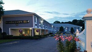 Un hotel con un letrero que dice 'AMBASSADOR INN & SOITES' y un estacionamiento.