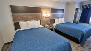 Habitación de hotel con dos camas, una mesita de noche con teléfono y una lámpara fijada a la pared.