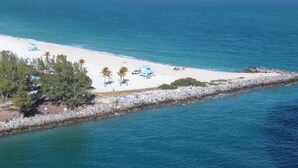 An aerial view of a beach with a rocky breakwater, palm trees, and a clear blue sea. - One Bal Harbour Hotel and Resort, Deluxe 2 bedroom private unit @ the Ritz (Bal Harbour)