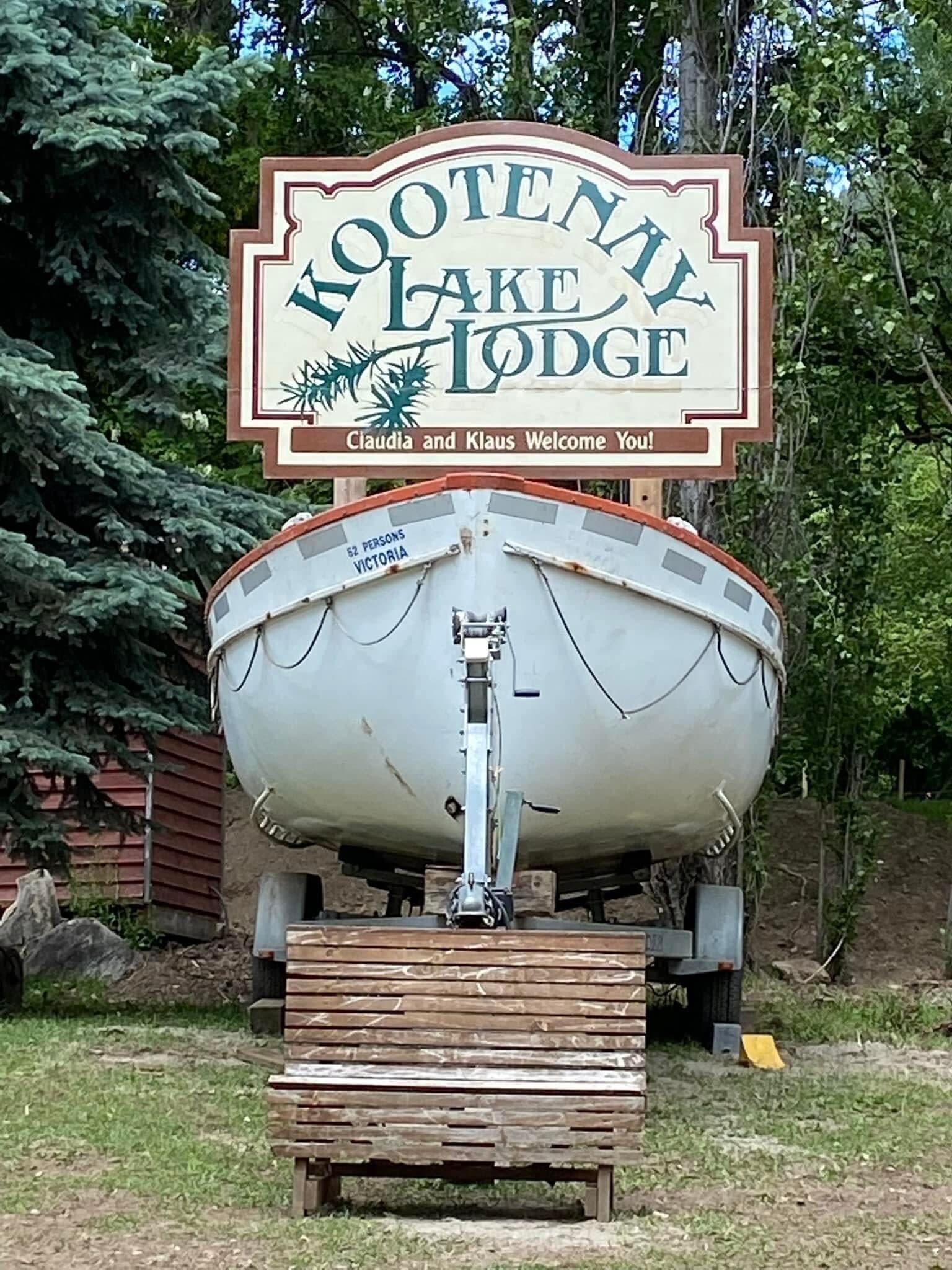 En båt med en skylt ovanför som visar texten ”Kootenay Lake Lodge” och ”Claudia och Klaus hälsar er välkomna!”.